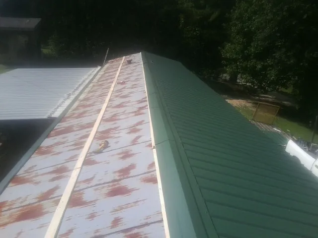 Old rusted panels beside newly installed green metal roofing — Wind Damage Roof Repair by Roofing Brothers in Fallston